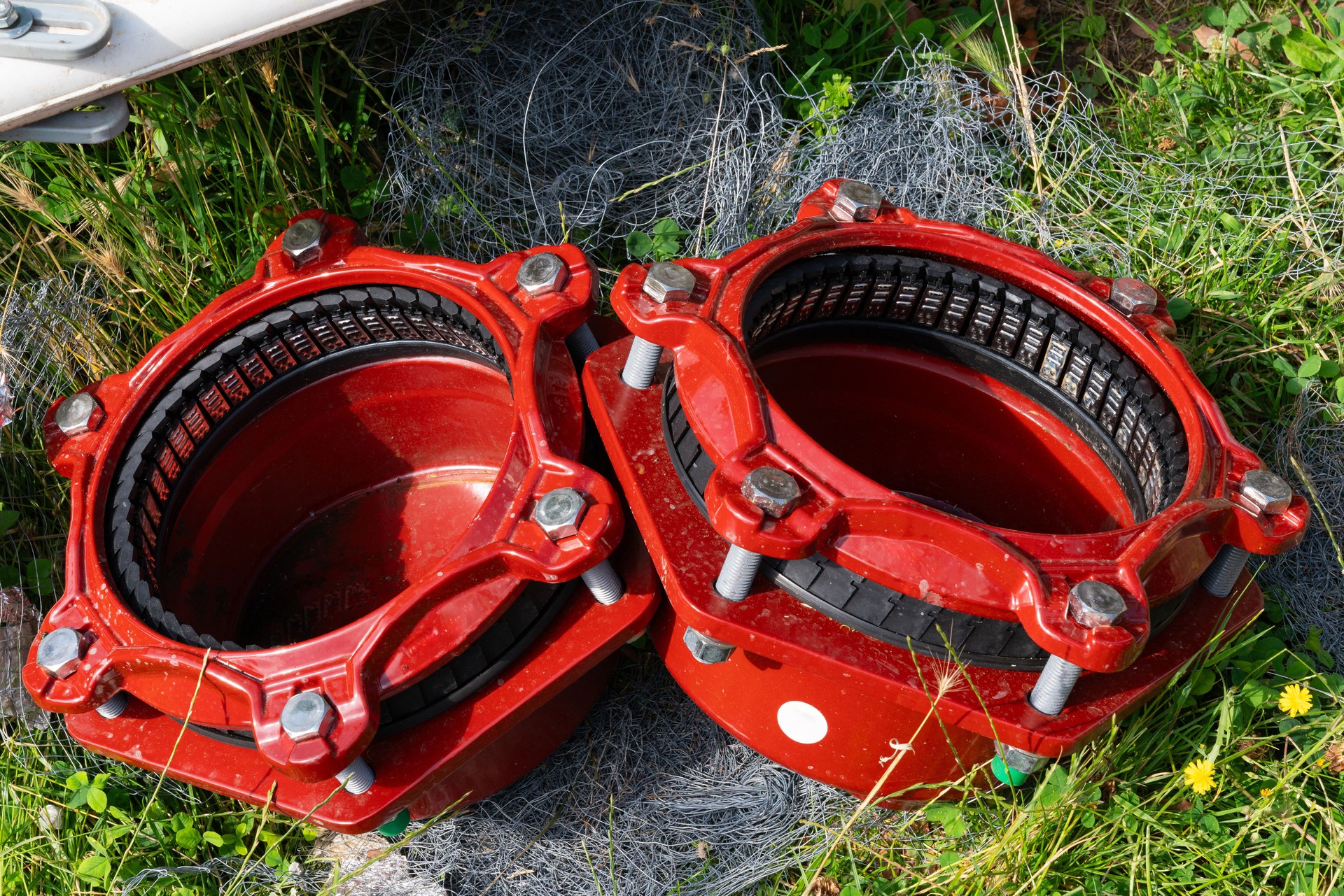 Two large red industrial pipe fittings lying in the grass.
